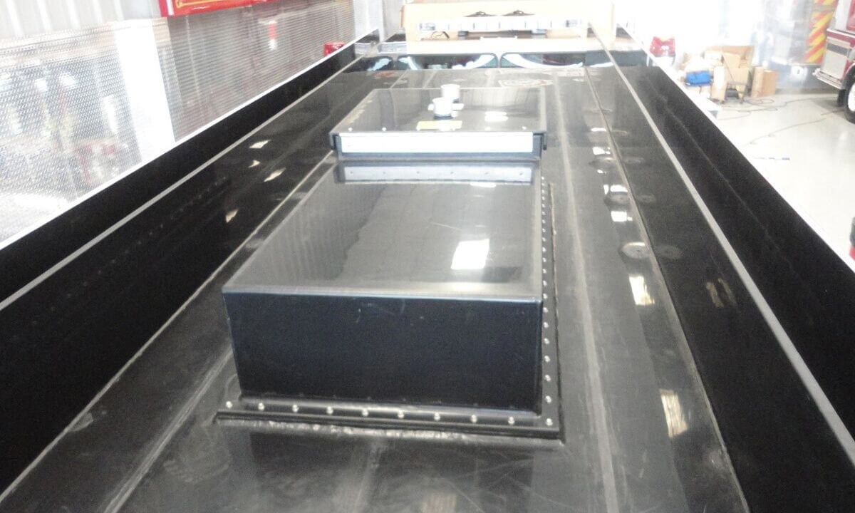 Tank integral hose bed storage areas